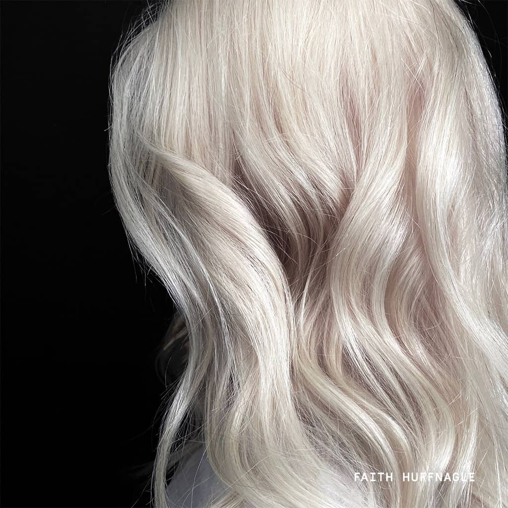 Blonde hair woman in white top in front of black background