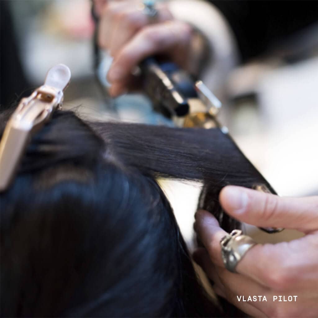 Hairtylist curling dark brown hair with curling iron